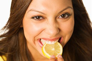 Женщина ест лимон
