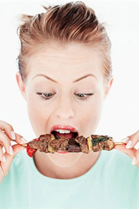 Женщина ест мясо