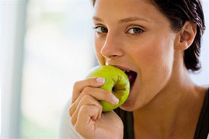 Женщина ест яблоко